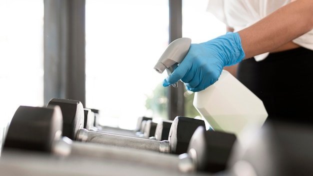 freepicdownloader.com woman with gloves cleaning solution disinfecting gym weights normal